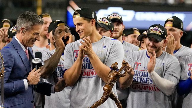 Texas Rangers shortstop Corey Seager stands by the trophy after Game 5 of the baseball World Series against the Arizona Diamondbacks Wednesday, Nov. 1, 2023, in Phoenix. (AP Photo/Brynn Anderson)