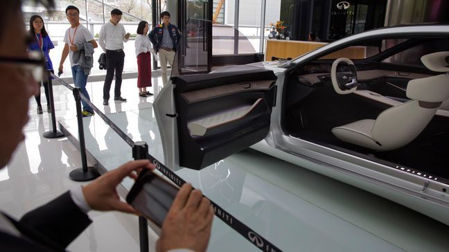 In this April 19, 2018, photo, visitors look at the Infiniti electric concept sedan at a showroom ahead of the Auto China 2018 to be held in Beijing, China. Auto China 2018, the biggest global auto show of the year, showcases China's ambitions to become a leader in electric cars and the industry's multibillion-dollar scramble to roll out models that appeal to price-conscious but demanding Chinese drivers. (AP Photo/Ng Han Guan)