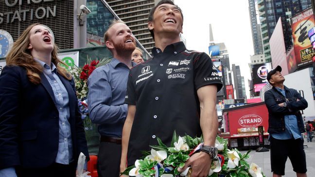 Takuma Sato, center, the 2017 Indianapolis 500 winner, watches his photos projected on the Nasdaq MarketSite in Times Square after ringing the opening bell, in New York, Tuesday, May 30, 2017. (AP Photo/Richard Drew)