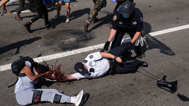 A Black Lives Matter protester and NYPD officers scuffle on the Brooklyn Bridge during a demonstration, Wednesday, July 15, 2020, in New York. Several New York City police officers were attacked and injured Wednesday on the Brooklyn Bridge during a protest sparked by the death of George Floyd, police said. At least four officers were hurt, including the department’s chief, and more than a dozen people were arrested.  (AP Photo/Yuki Iwamura)