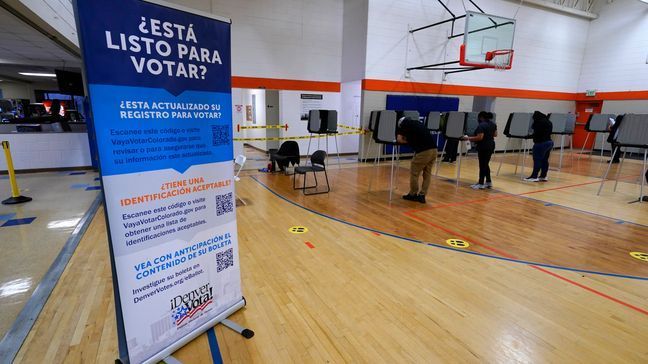 FILE - A sign in Spanish stands near voters as they cast their ballots at stations inside the La Familia Recreation Center in the Baker neighborhood Nov. 3, 2020, south of downtown Denver.    (AP Photo/David Zalubowski, File)