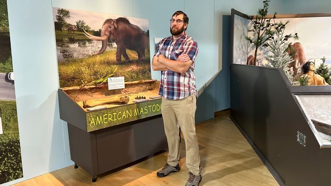 Cory Redman, science curator at the Grand Rapids Public Museum, stands near a mastodon display at the museum on Thursday, May 18, 2023, in Grand Rapids, Mich. (AP Photo/Mike Householder)