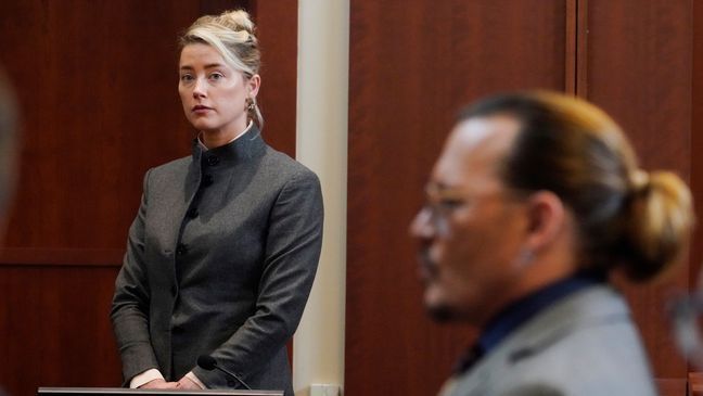 FILE - Actors Amber Heard and Johnny Depp watch as the jury leaves the courtroom for a lunch break at the Fairfax County Circuit Courthouse in Fairfax, Va., Monday, May 16, 2022.{&nbsp;} (AP Photo/Steve Helber, Pool, File)