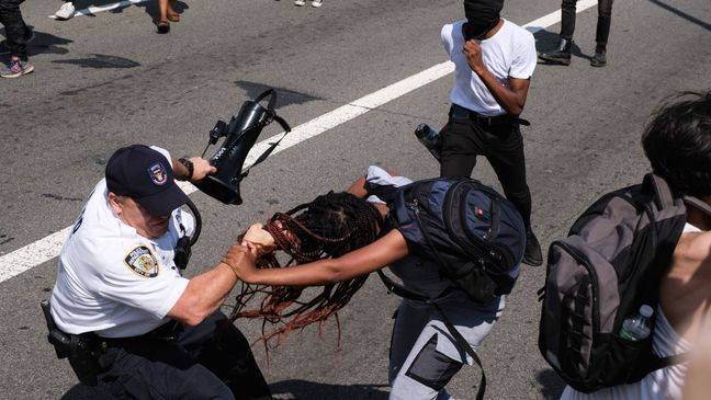 Black Lives Matter protesters scuffle with an NYPD officer on the Brooklyn Bridge in New York during a demonstration Wednesday, July 15, 2020. Several New York City police officers were attacked and injured during the protest, police said, and more than a dozen people were arrested.  (AP Photo/Yuki Iwamura)